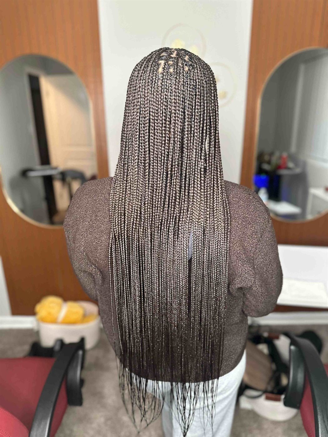 Small, waist-length knotless braids in the salon, with arched mirrors behind