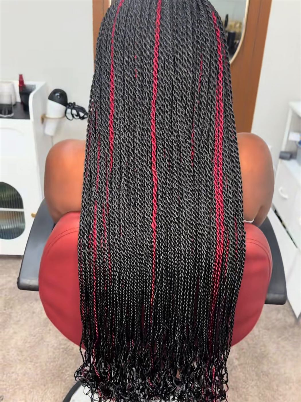 Long Senegalese twists with burgundy highlights, seen from behind in the salon chair